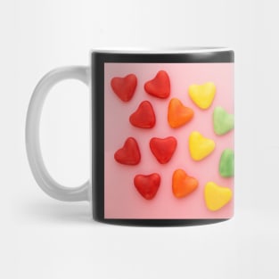 Heart-shaped colorful candy arranged in rainbow colors, on a pink background Mug